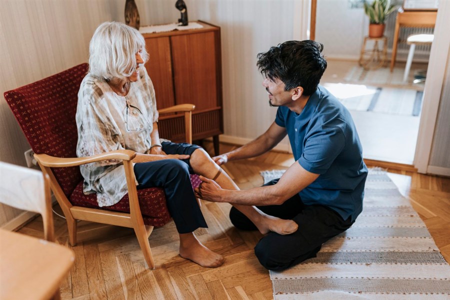 foto van een verzorgen die een oudere vrouw helpt